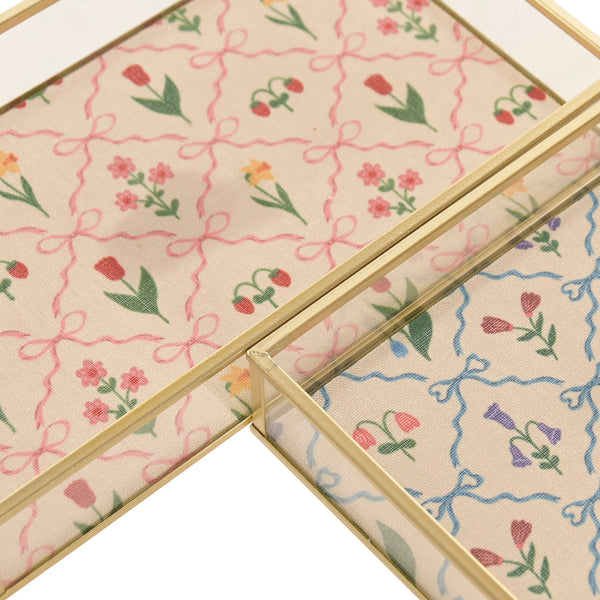 Detalle del estampado floral rosa de la bandeja decorativa de cristal y latón.