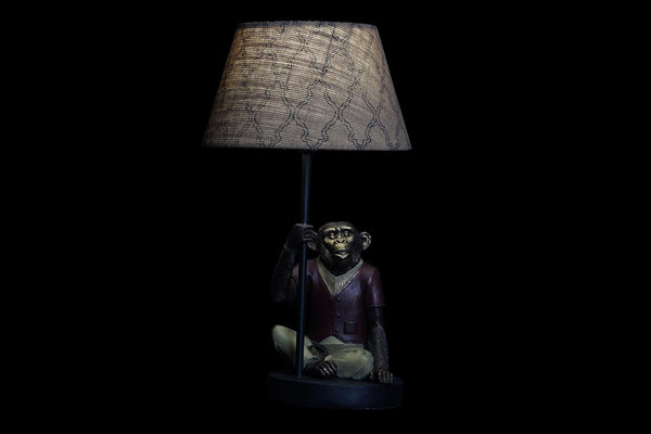 Lámpara encendida con figura de mono sobre fondo negro