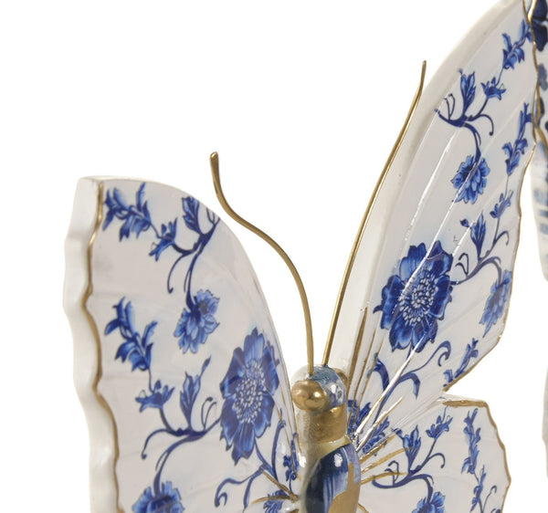 Detalle de mariposa azul y blanca de resina con flores y antenas doradas