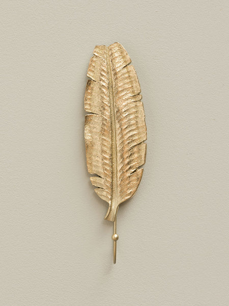 Percha decorativa hoja tropical dorada instalada en pared