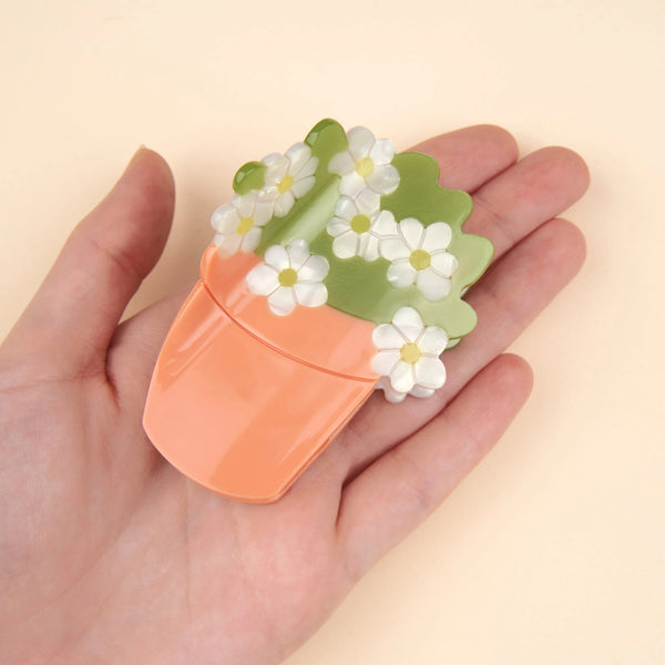 Pinza de pelo con forma de tiesto con flores blancas en man