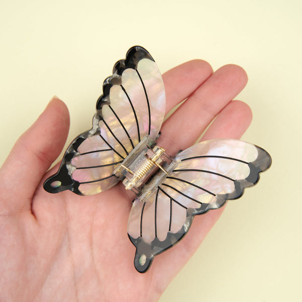 Pinza mariposa blanca sujeta en una mano - proporción real del accesorio