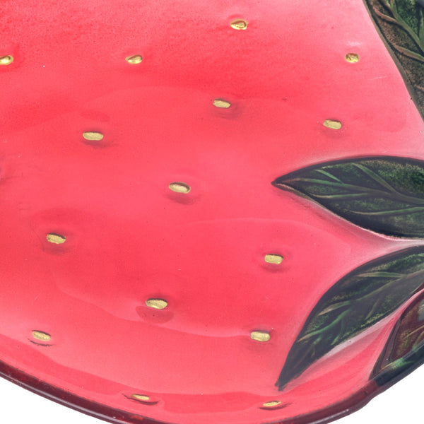 Detalle de plato de vidrio con semillas doradas y hojas en relieve.