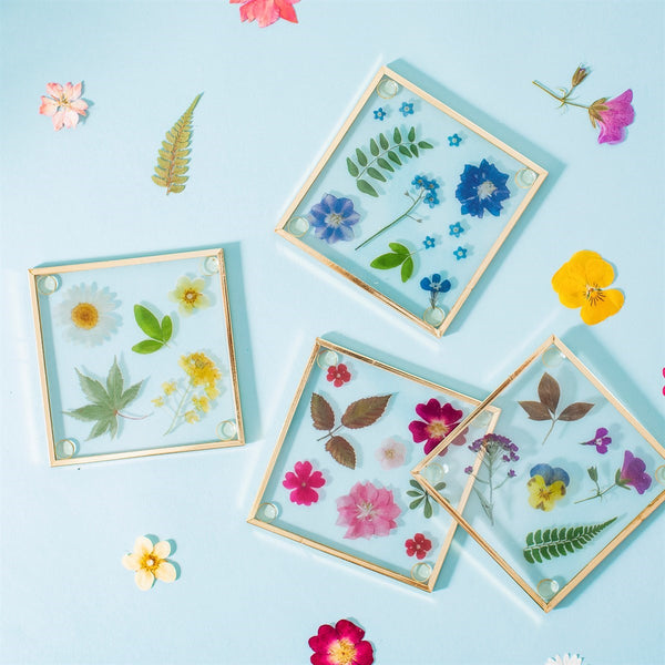 Conjunto de 4 porta-copos em forma de flor, feitos em metal e vidro.