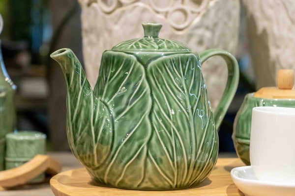 Detalle decorativo de tetera vegetal verde en mesa estilo rústico – Brocantia